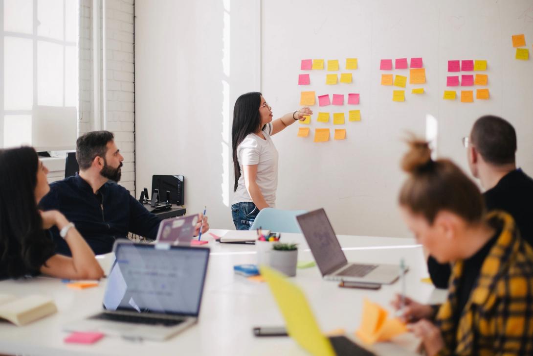 Woman putting post-its on a board for training purposes.